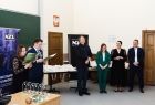 Studenci stojący na środku sali wykładowej, odbierający nagrody i wyróżnienia