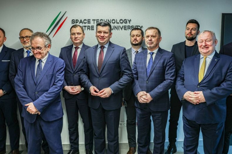 Uczestnicy wydarzenia stoją na sali przy logo centrum AGH.