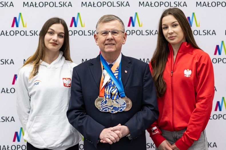 Wicemarszałek Witold Kozłowski z medalami na szyi. Obok dwie kobiety. 