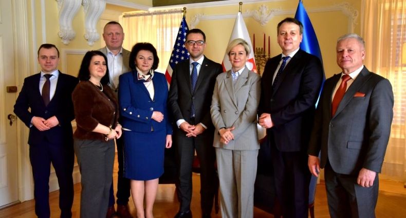 Radni województwa stoją z Konsulem RP w Nowym Jorku. W tle widoczne flagi.