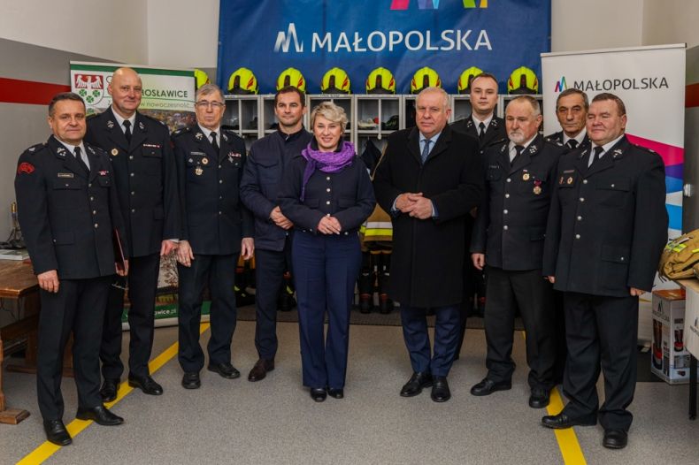 uczestnicy wydarzenia stoją w remizie. Z tyłu widoczny napis Małopolska.