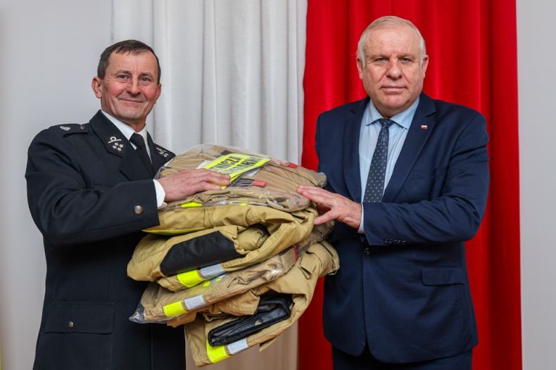 Wicemarszałek Ryszard Pagacz przekazuje strażakowi mundury.