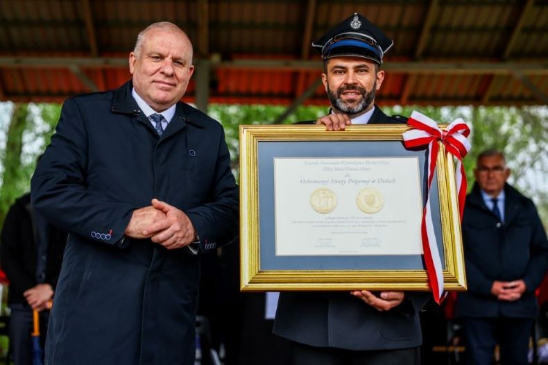 Wicemarszałek Ryszard Pagacz stoi ze strażakiem i medalem Polonia Minor.