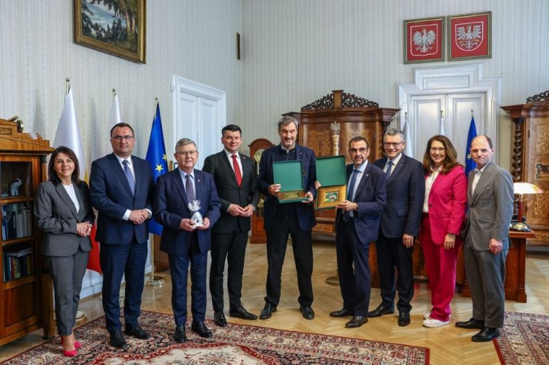 Uczestnicy spotkania stoją razem z gabinecie.