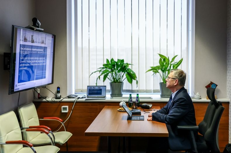 Wicemarszałek Witold Kozłowski przed ekranem w trakcie telekonferencji.