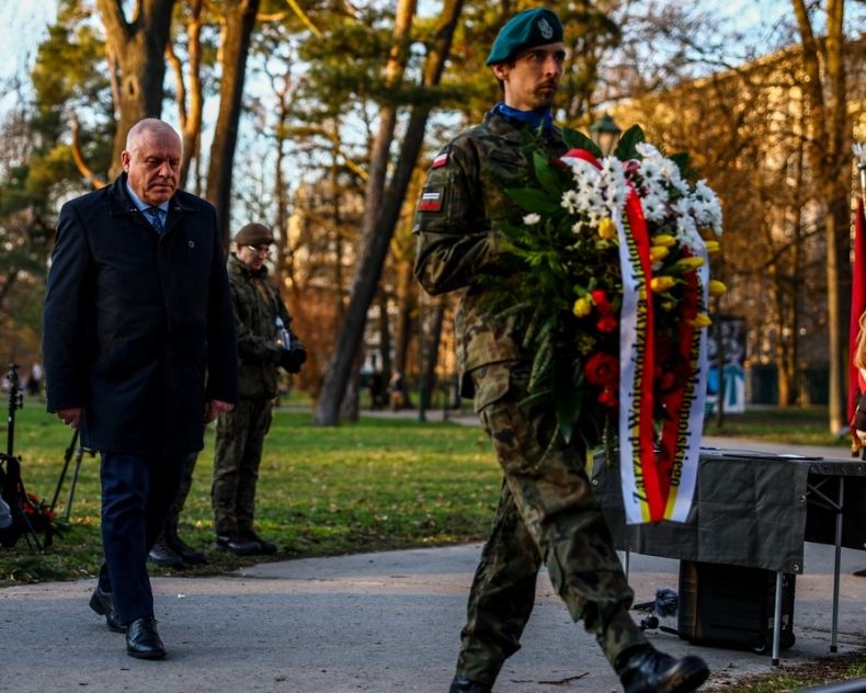 Wicemarszałek Ryszard Pagacz idzie za żołnierzem trzymającym wieniec.