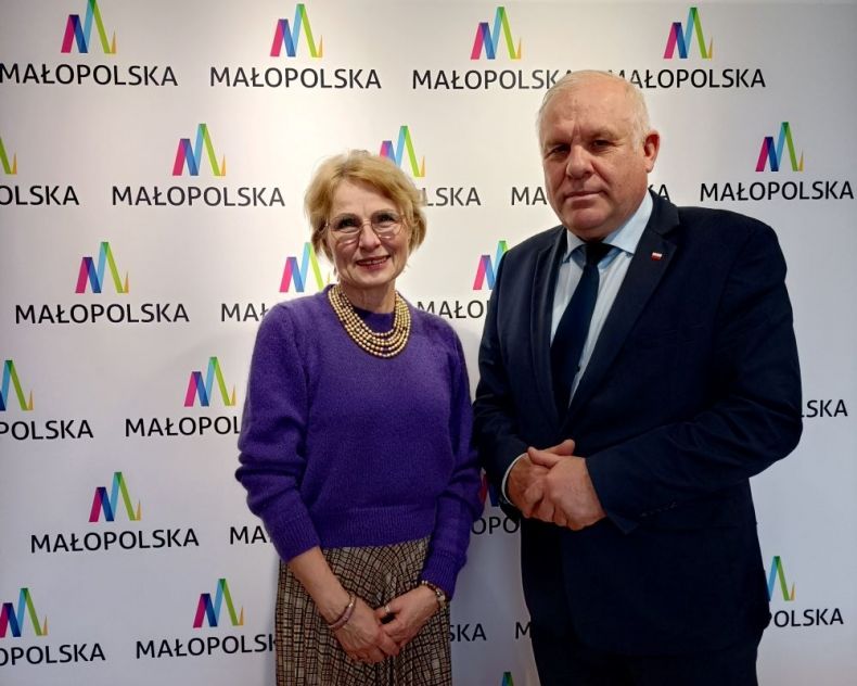 Wicemarszałek Ryszard Pagacz stoi z kobietą na tle ścianki z napisem Małopolska.