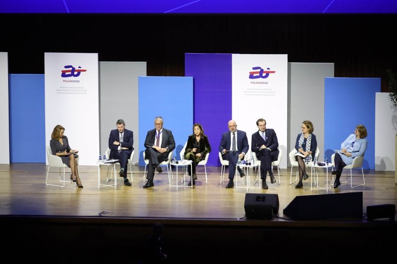 Grupa ludzi siedząca na scenie. 