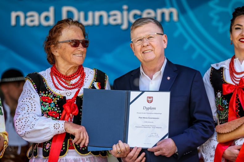 Wicemarszałek Witold Kozłowski i kobieta w stroju regionalnym trzymający dyplom.