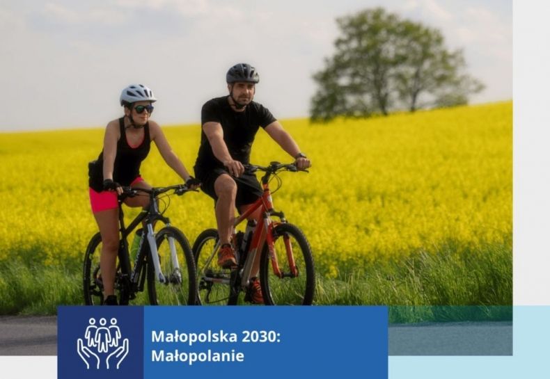 Mężczyzna i kobieta jadą na rowerach. W tle widoczne pola rzepaku i drzewa.