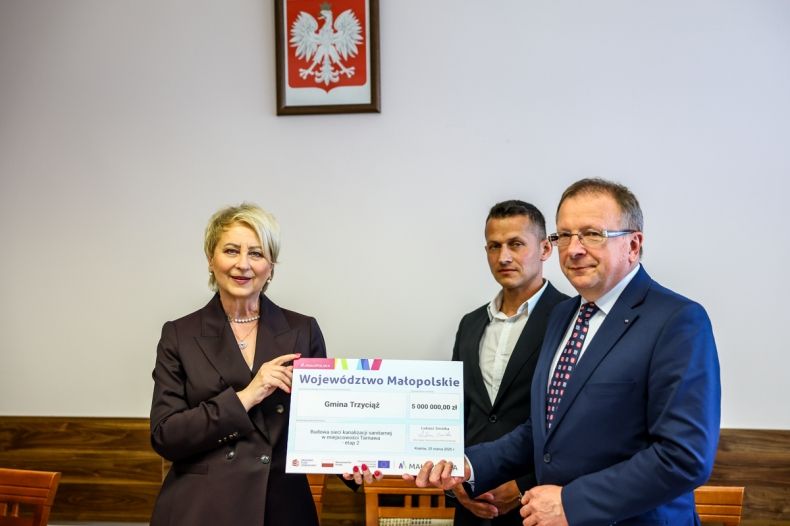 Iwona Gibas z Zarządu Województwa Małopolskiego przekazuje samorządowcom z Trzyciąża promesę, symboliczny czeka na 5 milionów złotych 