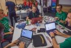 Zdjęcie przedstawia młodych ludzi na BeaconValley Conference 2016, siedzacych przy stole i pracujących na laptopach.