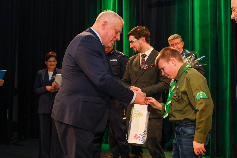 Wicemarszałek Ryszard Pagacz wręcza prezent harcerzowi.