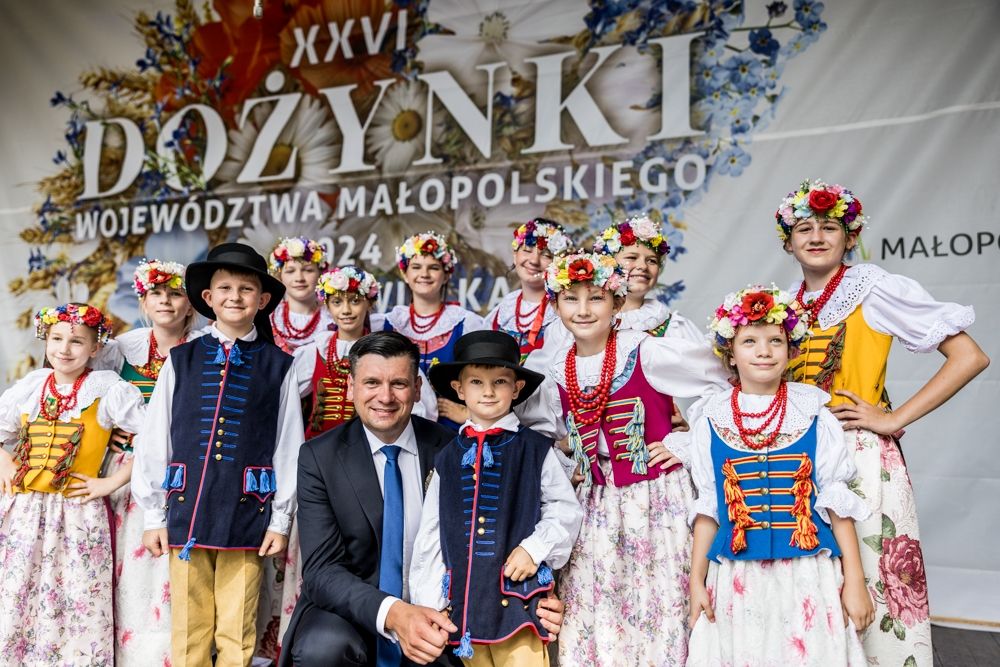 Marszałek Województwa Małopolskiego otoczony dziećmi w strojach regionalnyc podczas dożynek w 2024 roku