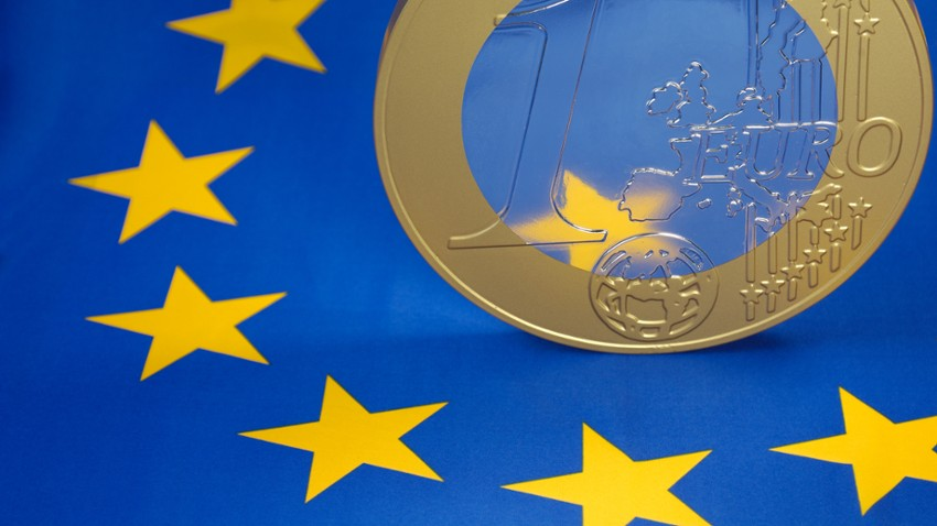 Zdjęcie ilustrujące fundusze Interreg. Moneta euro na tle flagi UE