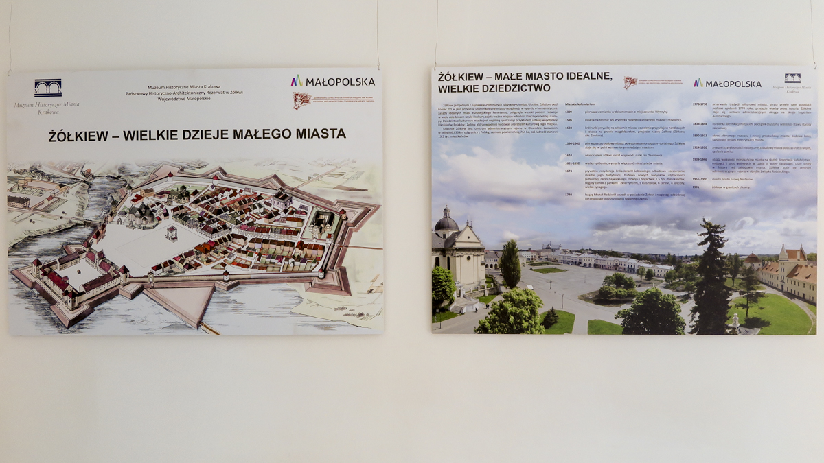 Zdjęcie dwóch planszy przedstawiających miejscowość Żółkiew. Plansze wiszą na białej ścianie.
