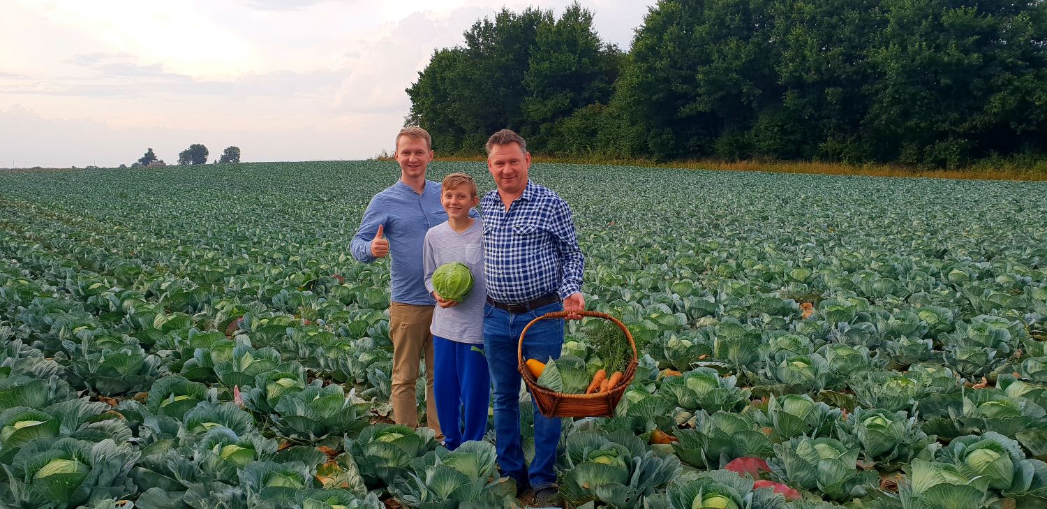 Dwaj męźczyźni i chłopiec stojących w środku pola kapusty.