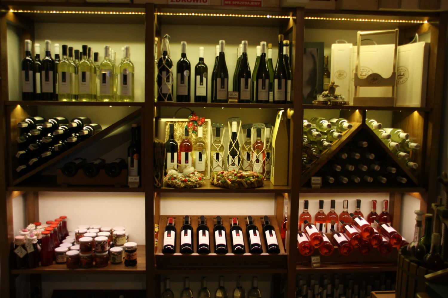 Duża podświetlana witryna z winami ułożonymi na trzech poziomach.
