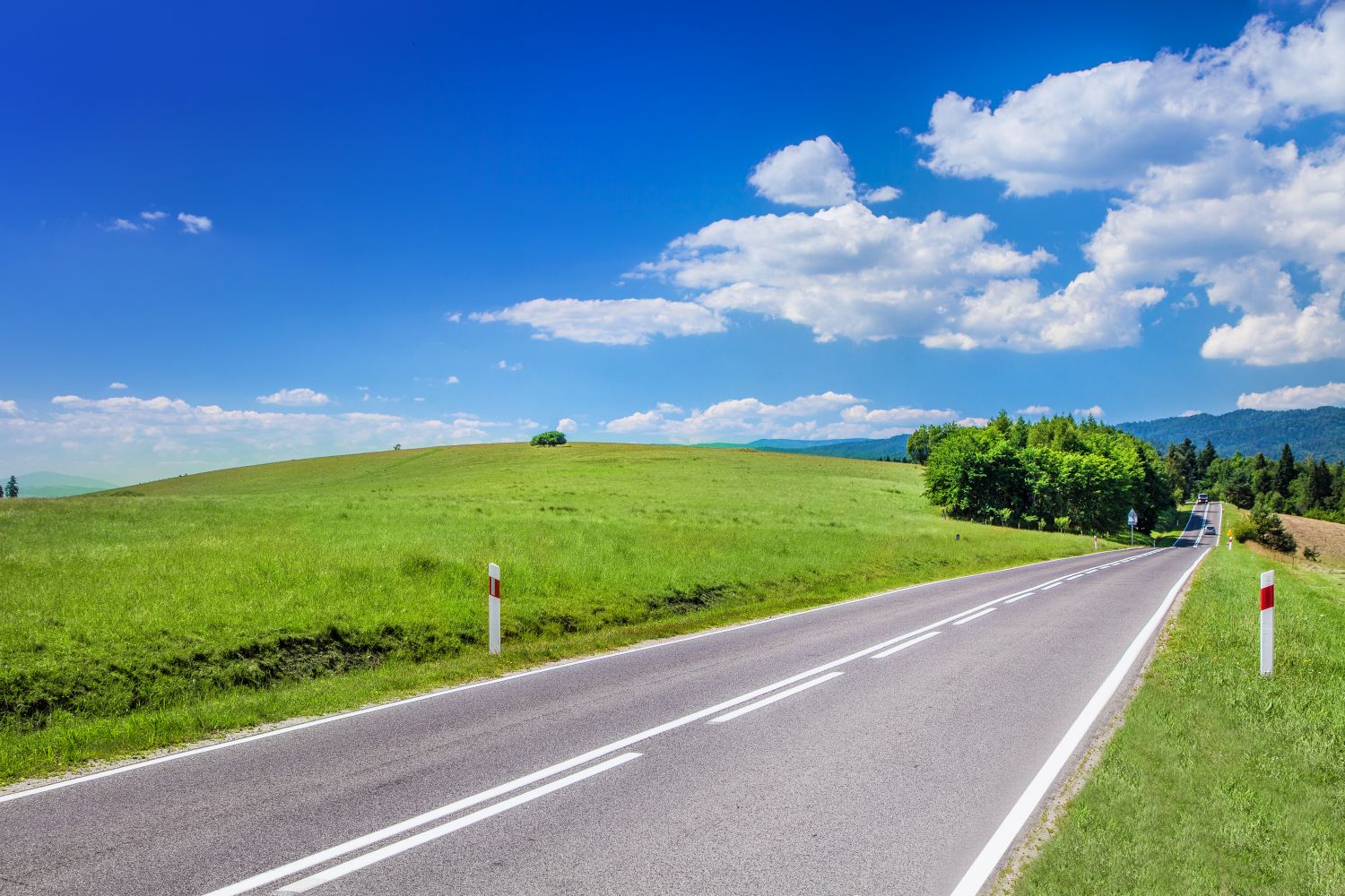 Zdjęcie przedstawia drogę, w tle znajduje się górzysty krajobraz