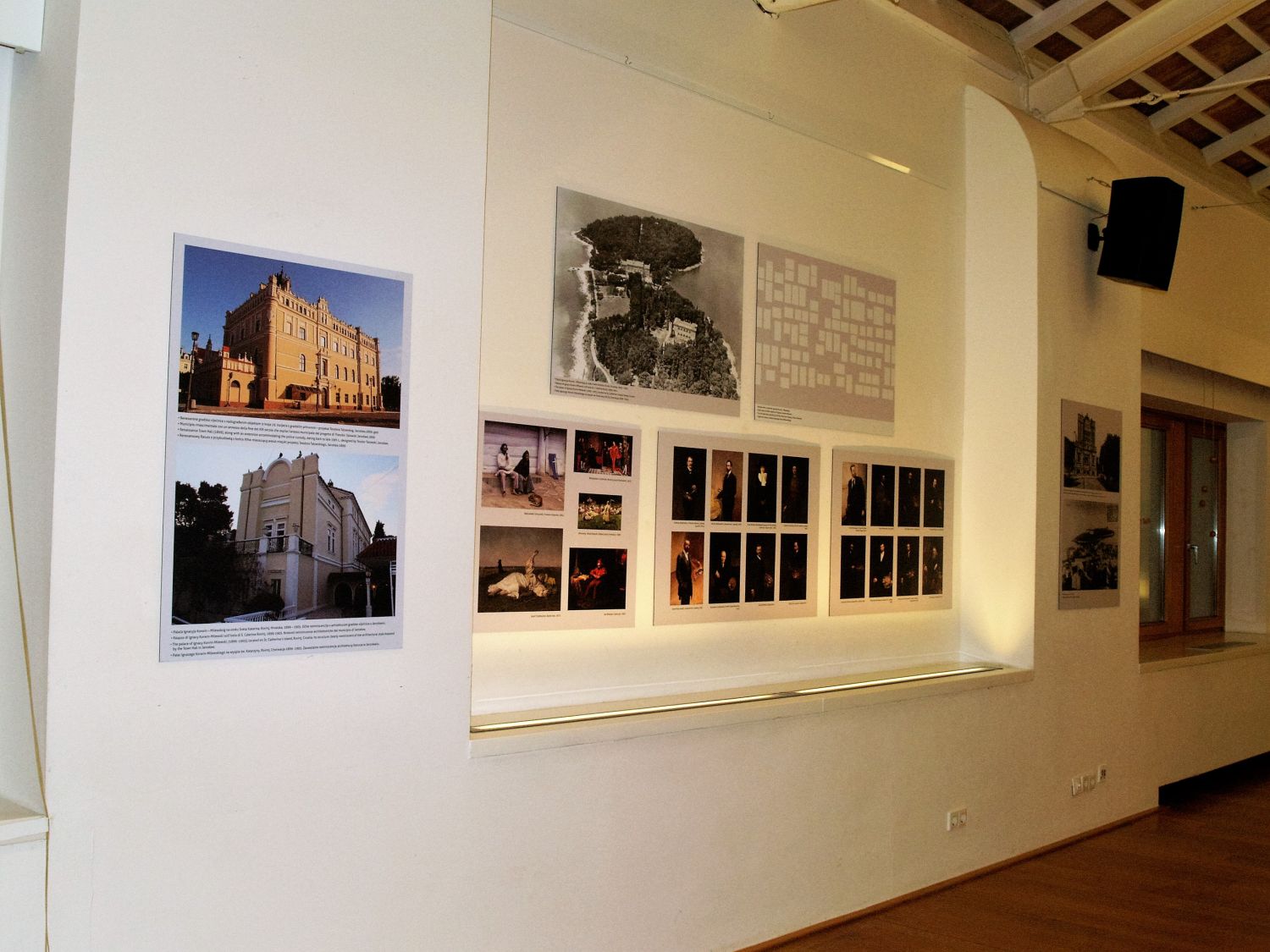 Na zdjęciu widać zbliżenie ściany, na której wiszą obrazy, plasze z tekstami, zdjęcia przedstawiające budynki.